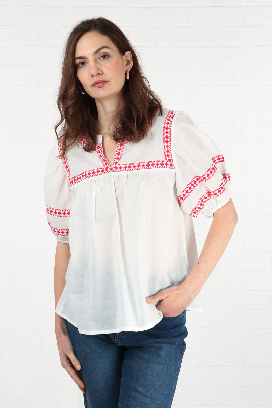 model wearing a short sleeved cotton blouse with red embroidery on the sleeves and neck area