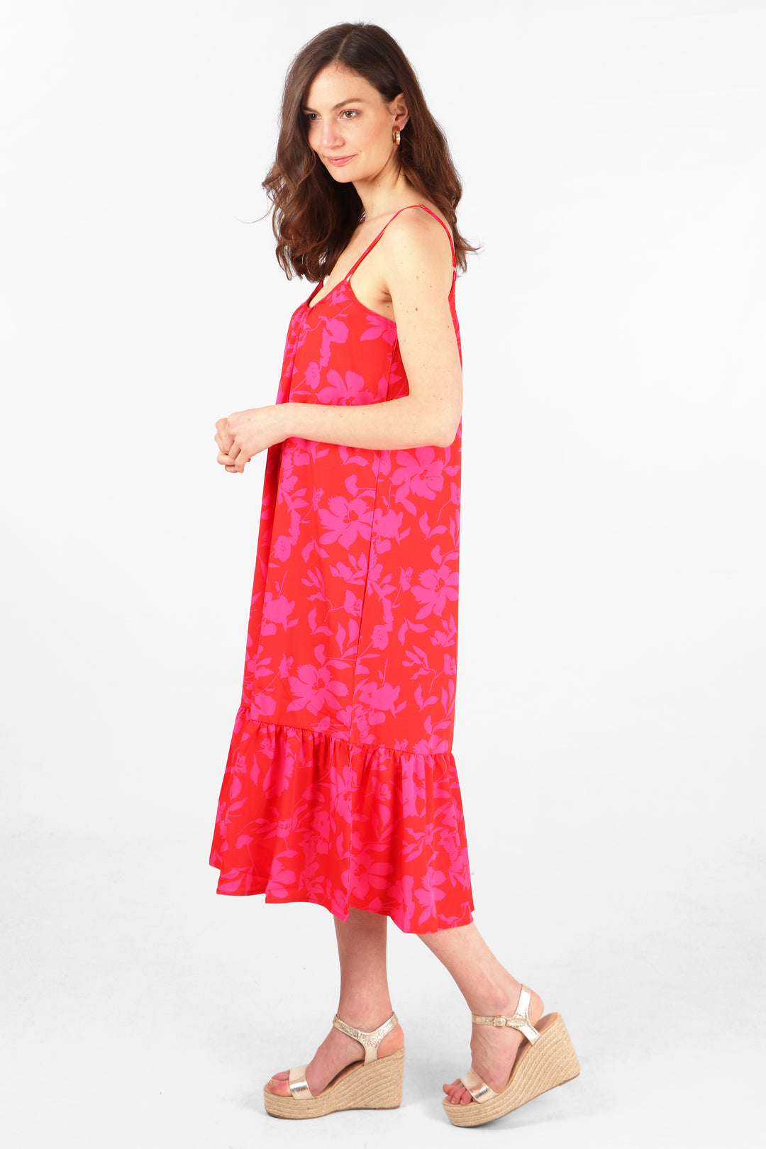 model wearing a red and pink floral print midi slip dress with spaghetti straps and a tiered hem