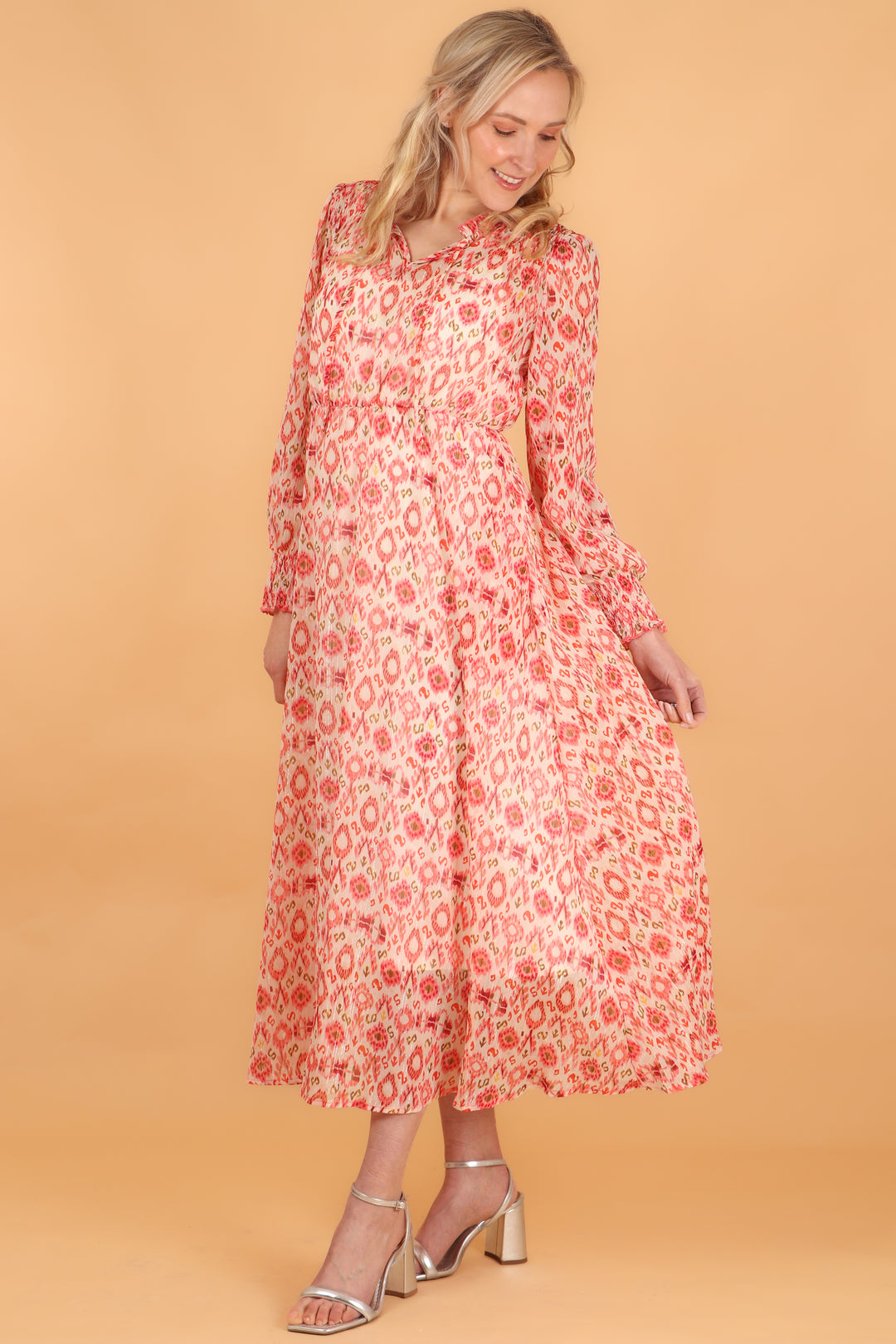 model showing the loose floaty design on this midi length long sleeve coral ikat dress