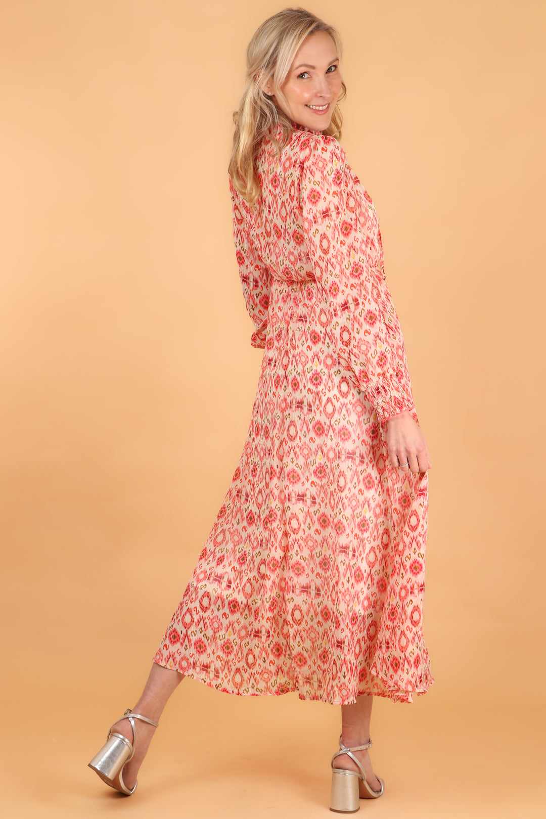 model showing the back of the dress with the all over coral orange ikat print