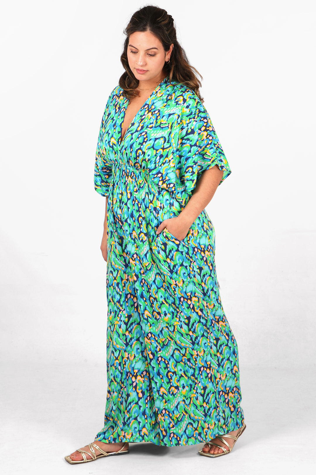 model wearing a green abstract print jumpsuit with full length flared trouser legs, v neck and elbow length angel sleeves
