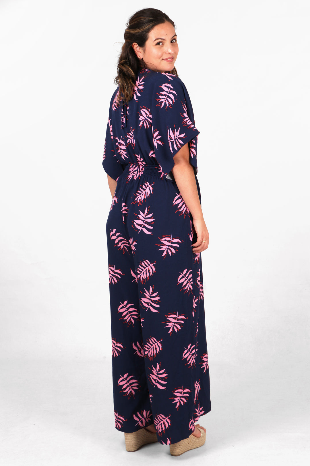 model showing the back of the jumpsuit and the all over palm leaf pattern