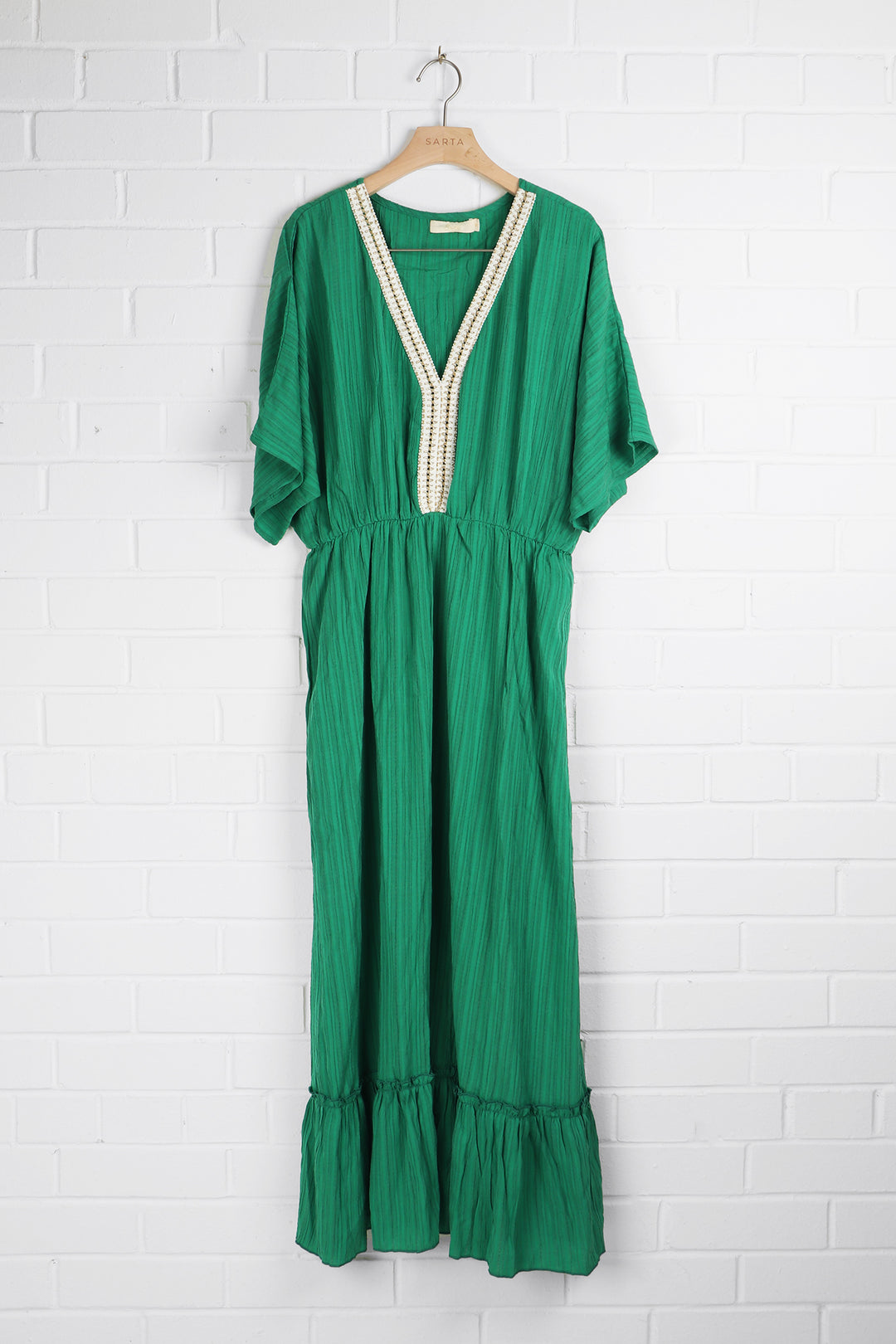 green tiered kaftan dress with gold robe details around the neck, draped on a coat hanger