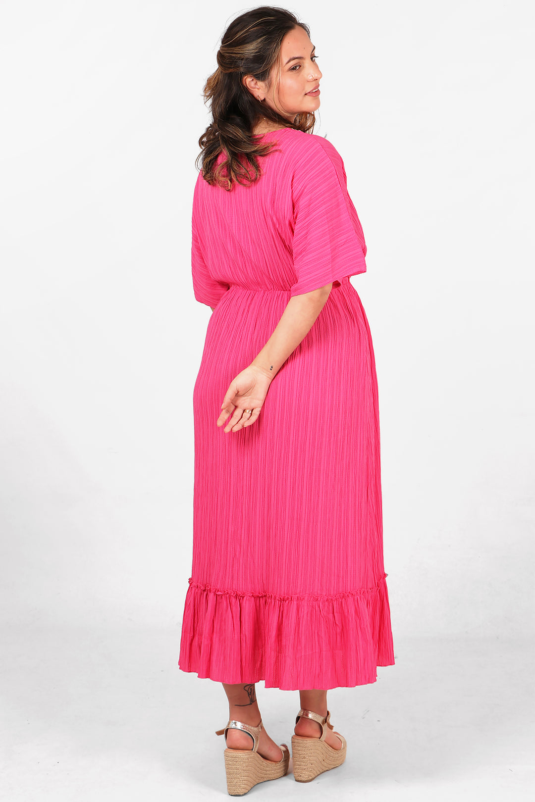 model showing the back of the midi dress, showing an all over pink colour with textured fabric