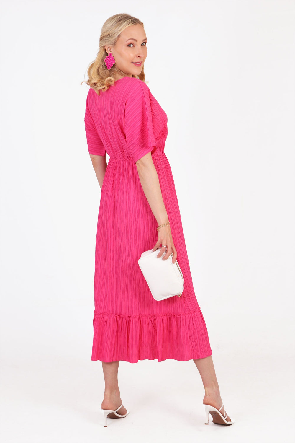 model showing the back of the pink midi kaftan dress, showing the tiered hem and the all over colour