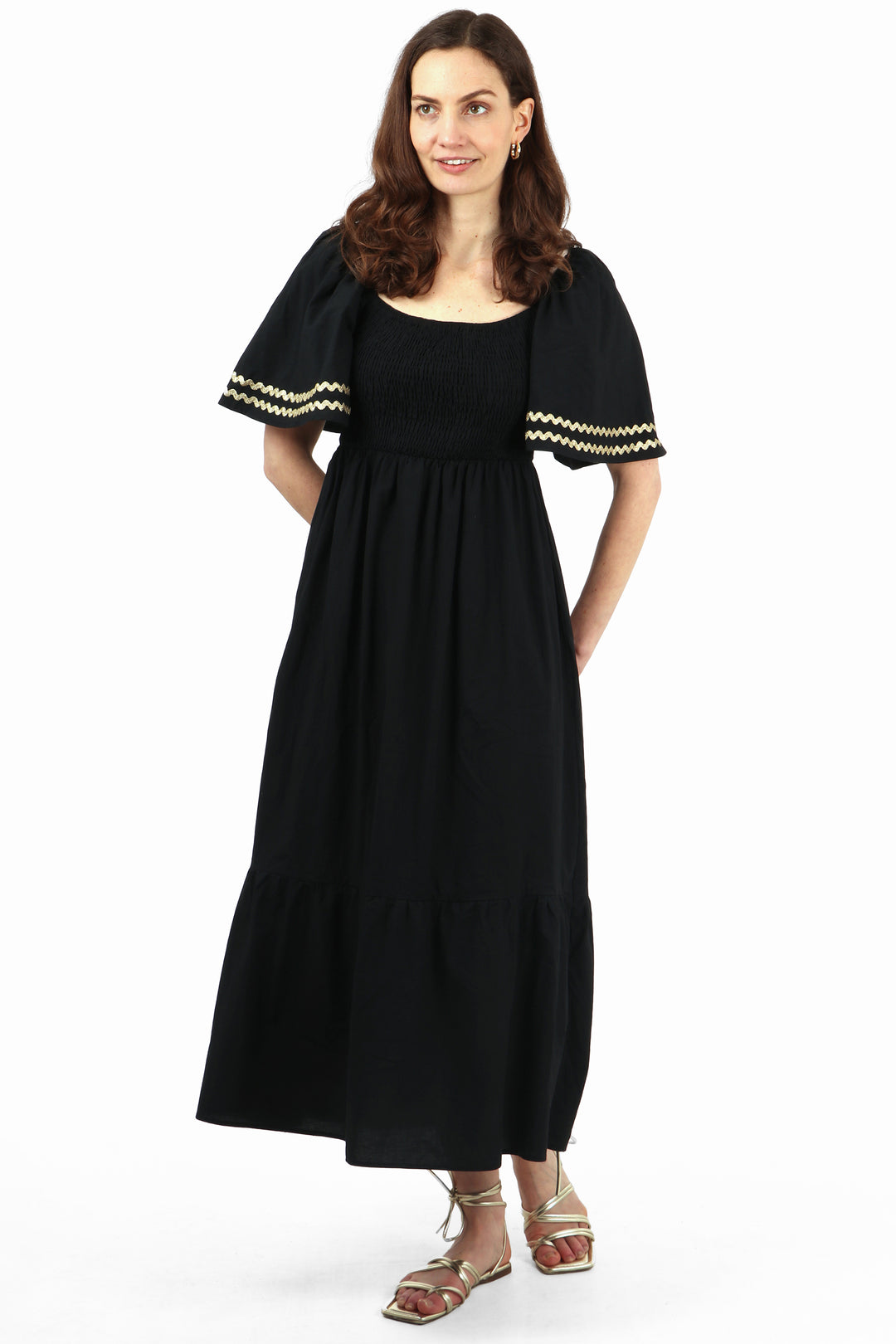 model wearing a maxi milkmaid dress with shirred bodice and short bell sleeves with a gold zig zag stripe trim