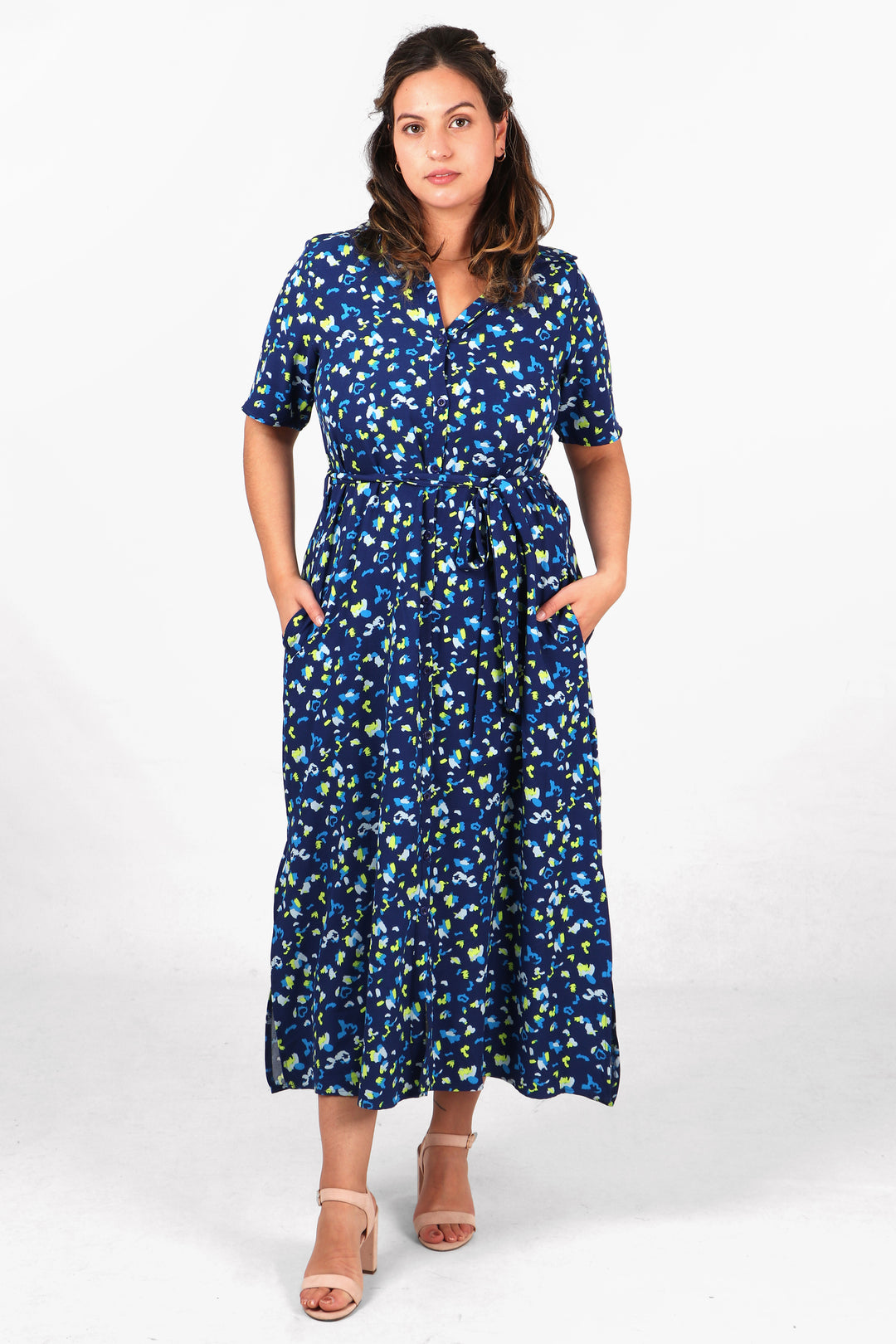 model wearing a midaxi length shirt dress with short sleeves, waist tie and an all over navy blue, yellow and white abstract print pattern