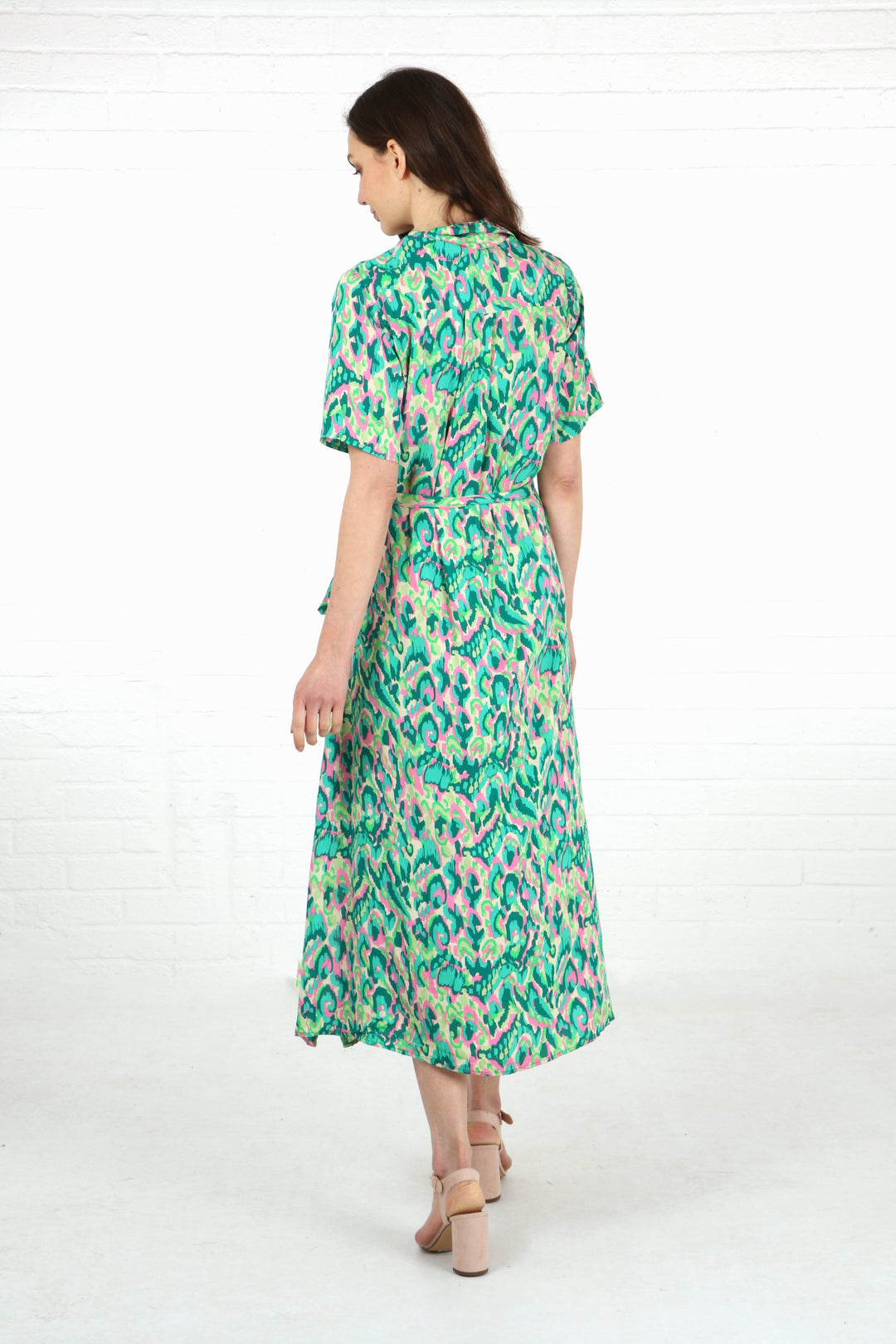 model showing the back of the green abstract print shirt dress showing the subtle dipped hem design