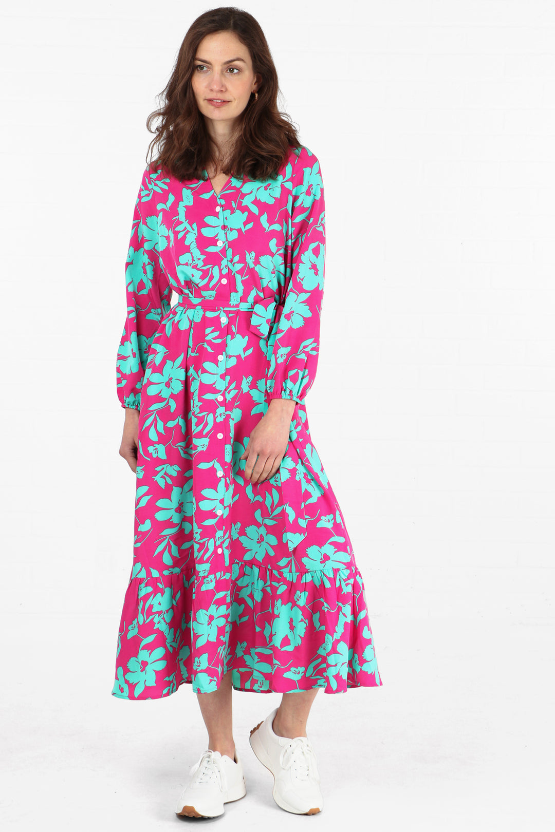 model wearing a maxi tiered shirt dress in a pink and turquoise tropical floral print pattern