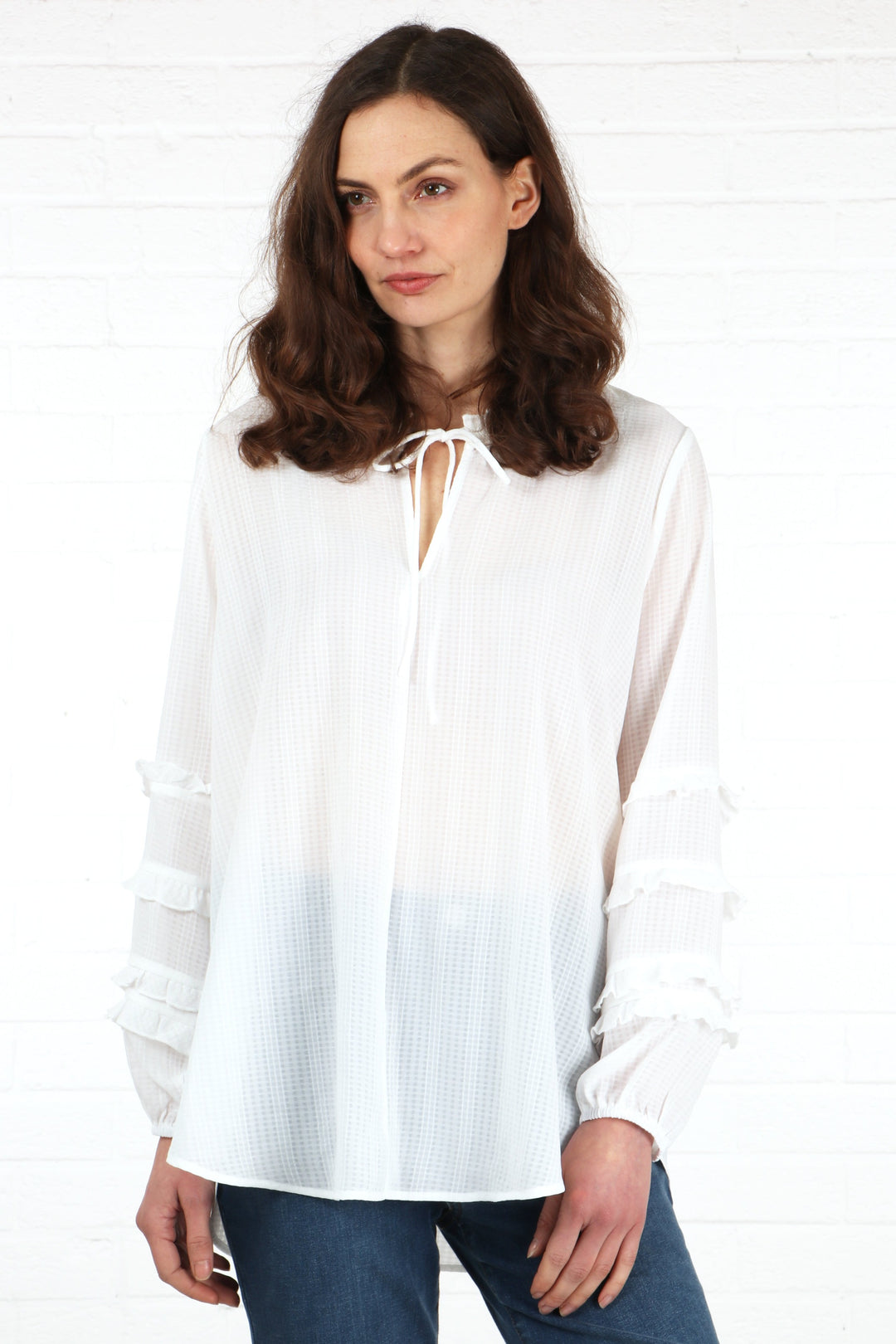 model wearing a lightweight white long sleeve blouse with frill sleeves and a grandad collar