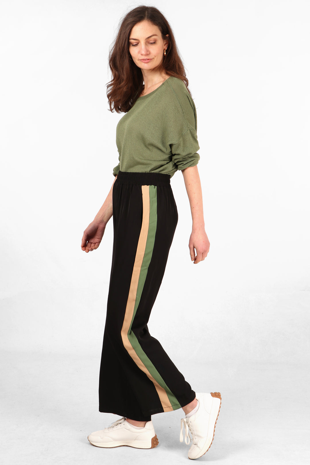 model wearing long black trousers withbeige and khaki stripes running the length of the leg at the side of the trousers