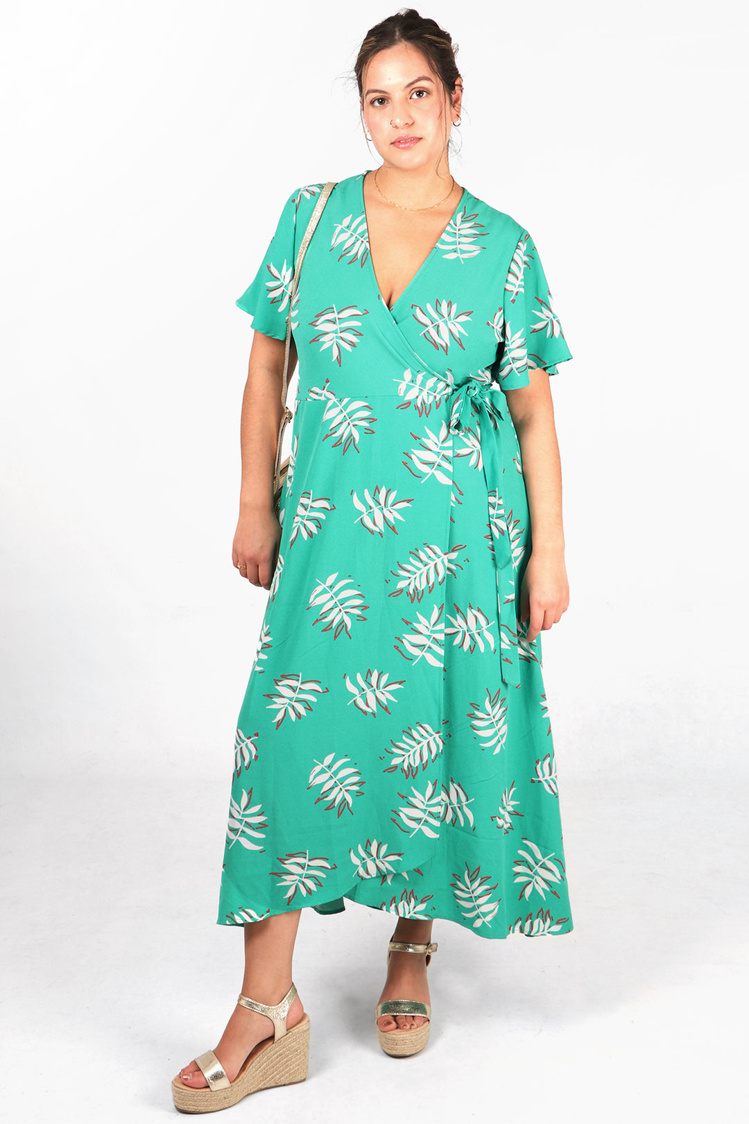 model wearing green short sleeved wrap dress with a whitea and coral palm leaf pattern all over