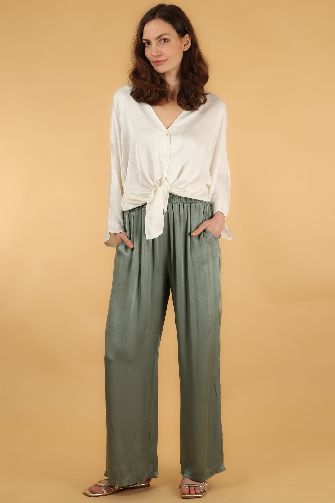 model wearing a pair of plain sage green wide leg trousers with pockets