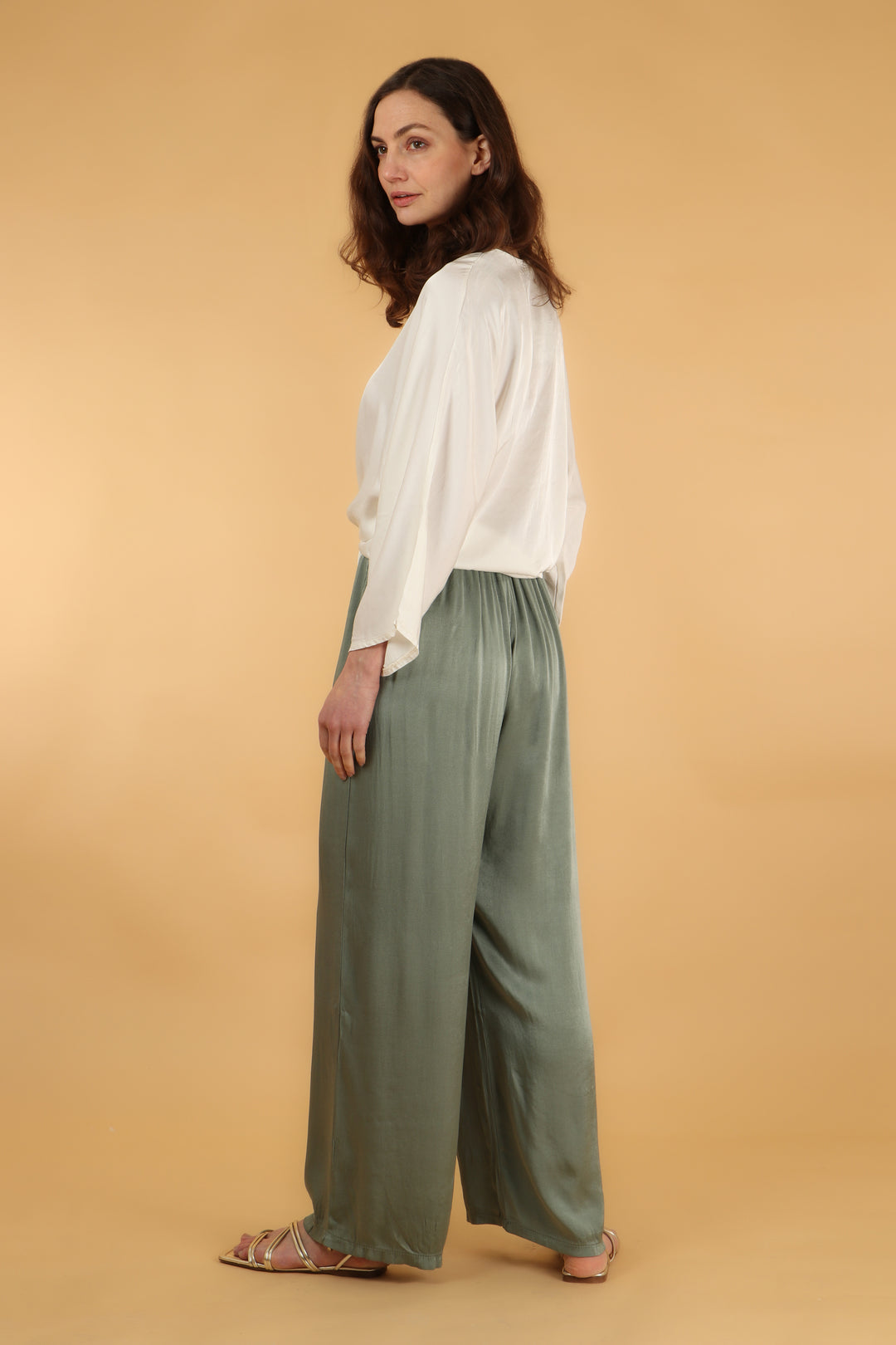 model showing the back of the sage green trousers showing an all over solid colour
