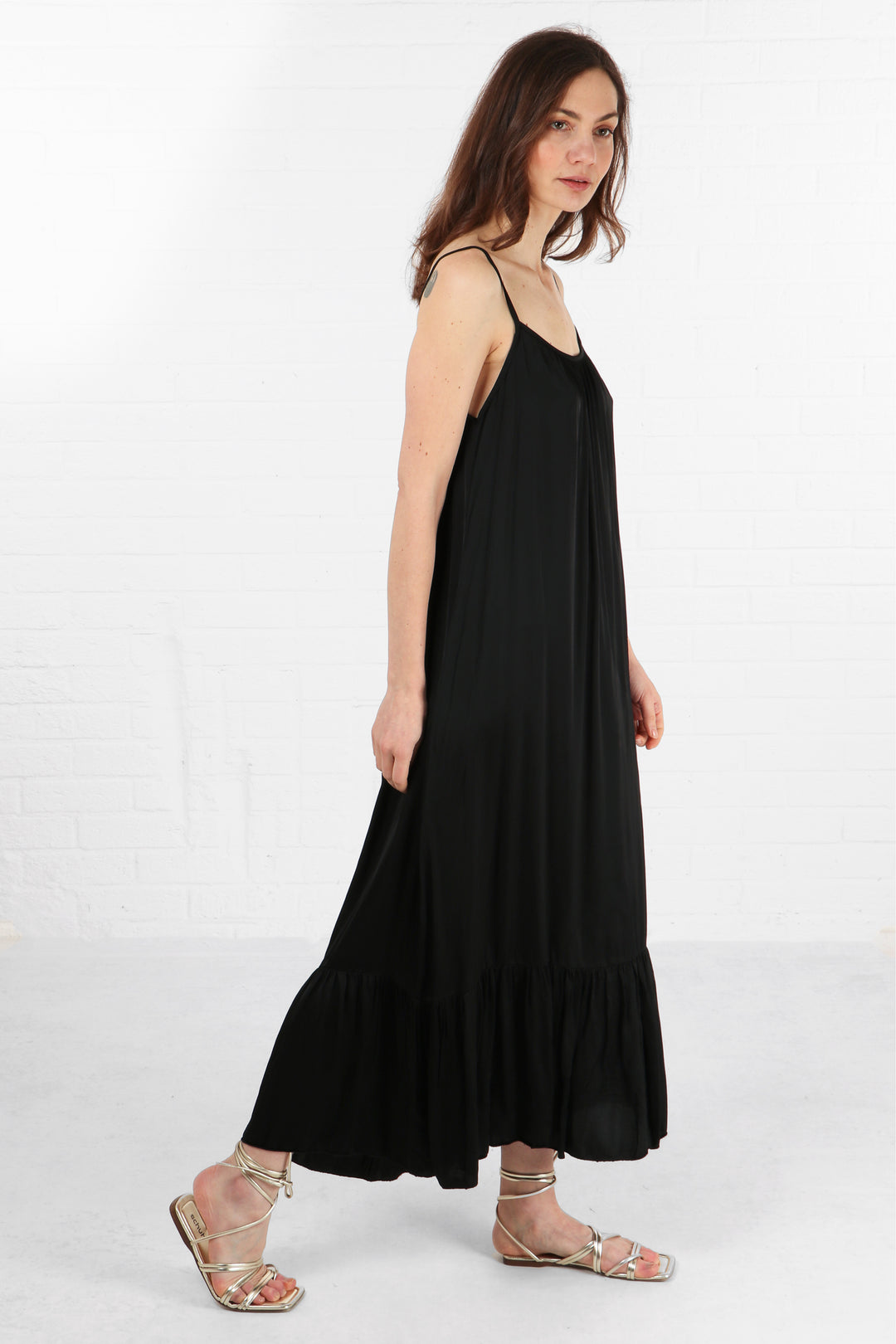 model wearing a black tiered maxi dress with thin spaghetti staps