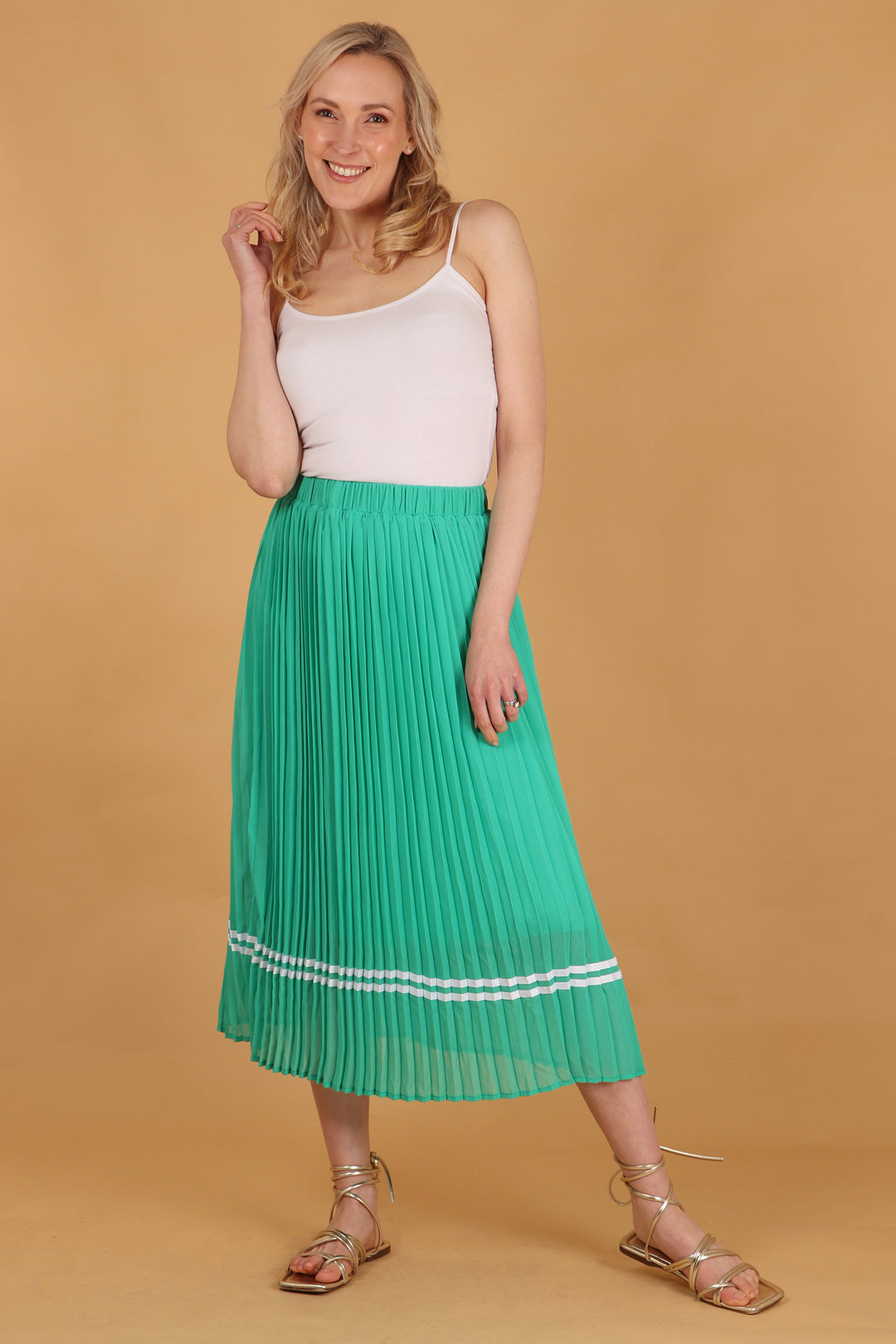 model wearing a green pleated midi skirt with two white stripes near the hem, the stripes are ribbon stripes 