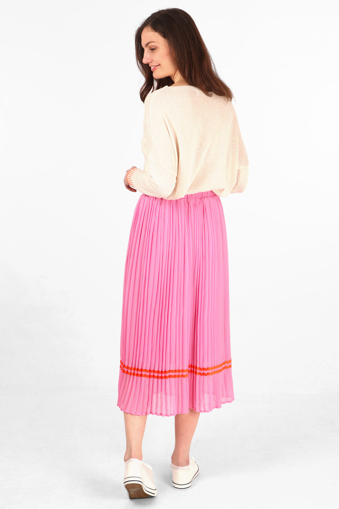 model showing the back of the pink pleated midi skirt showing an all around orange ribbon trim