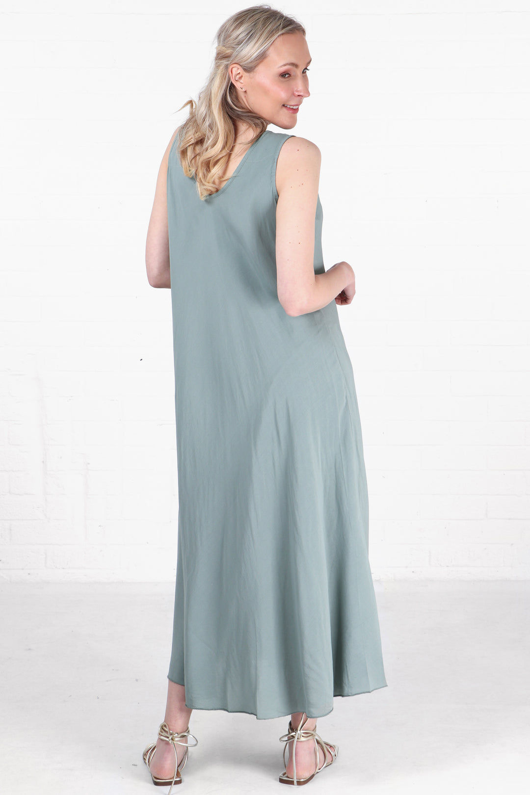 model showing the back of the dress which is the same solid sage green colour as the front, v neck on the back as well as the front