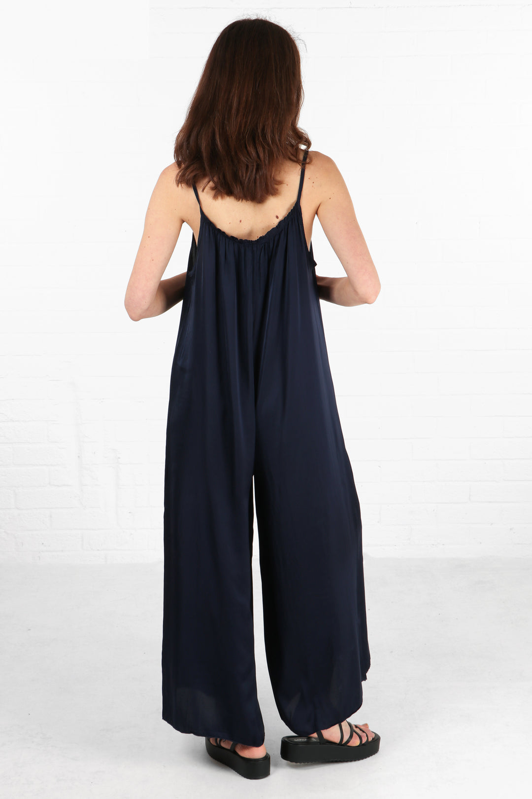 model showing the back of the navy blue jumpsuit showing the scoop neck design at the back