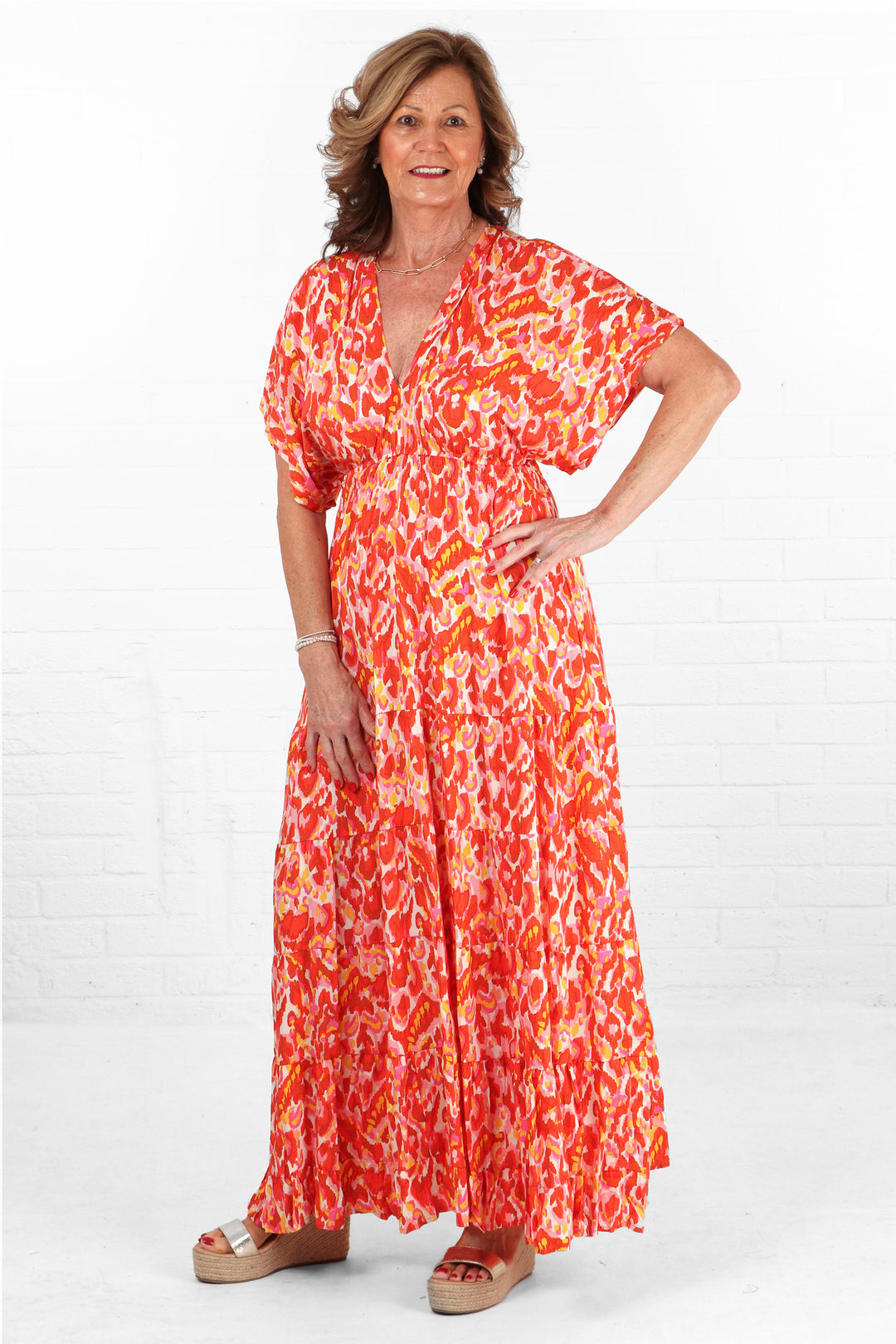 model wearing a coral orange v neck maxi kaftan dress with short sleeves and a v neck