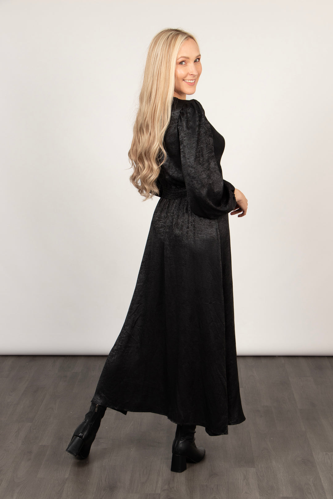 model showing the back of the metallic black dress, showing the hemline sitting midcalf
