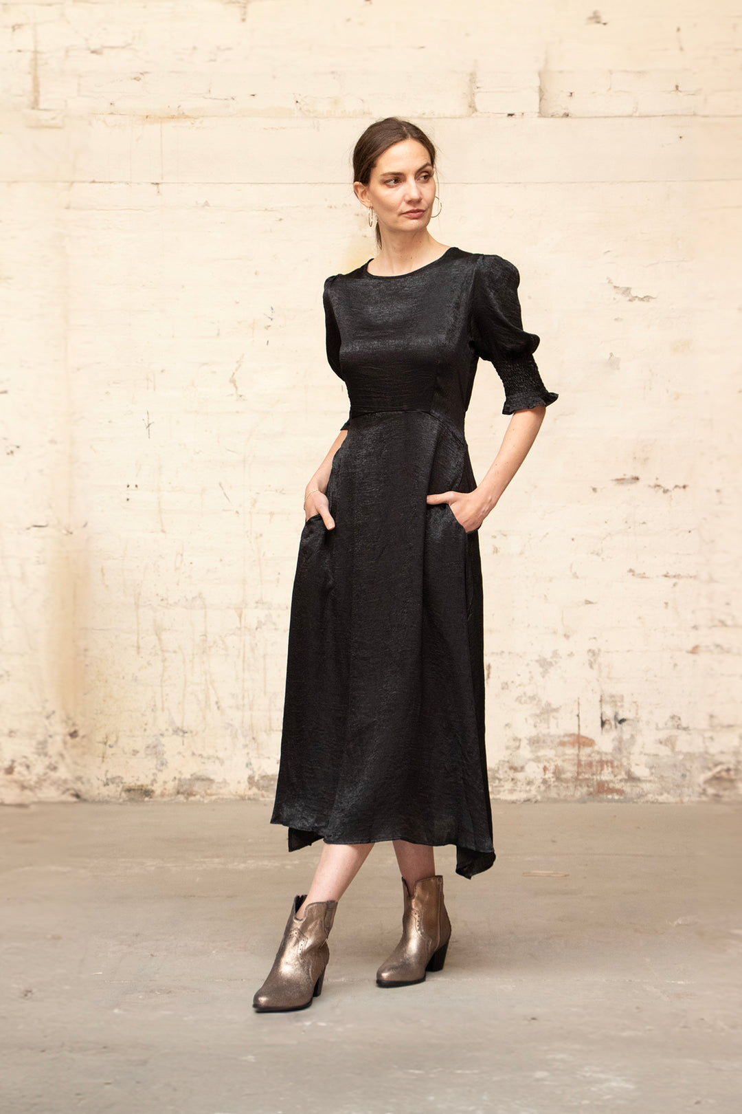 model wearing a black metallic midi tea dress with 3/4 puff sleeves and a round neck