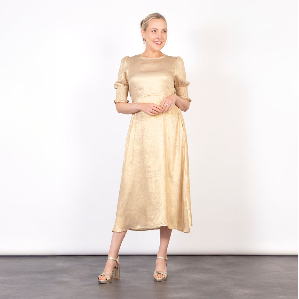 model wearing a champagne gold midi tea dress with 3/4 puff sleeves and a round neck