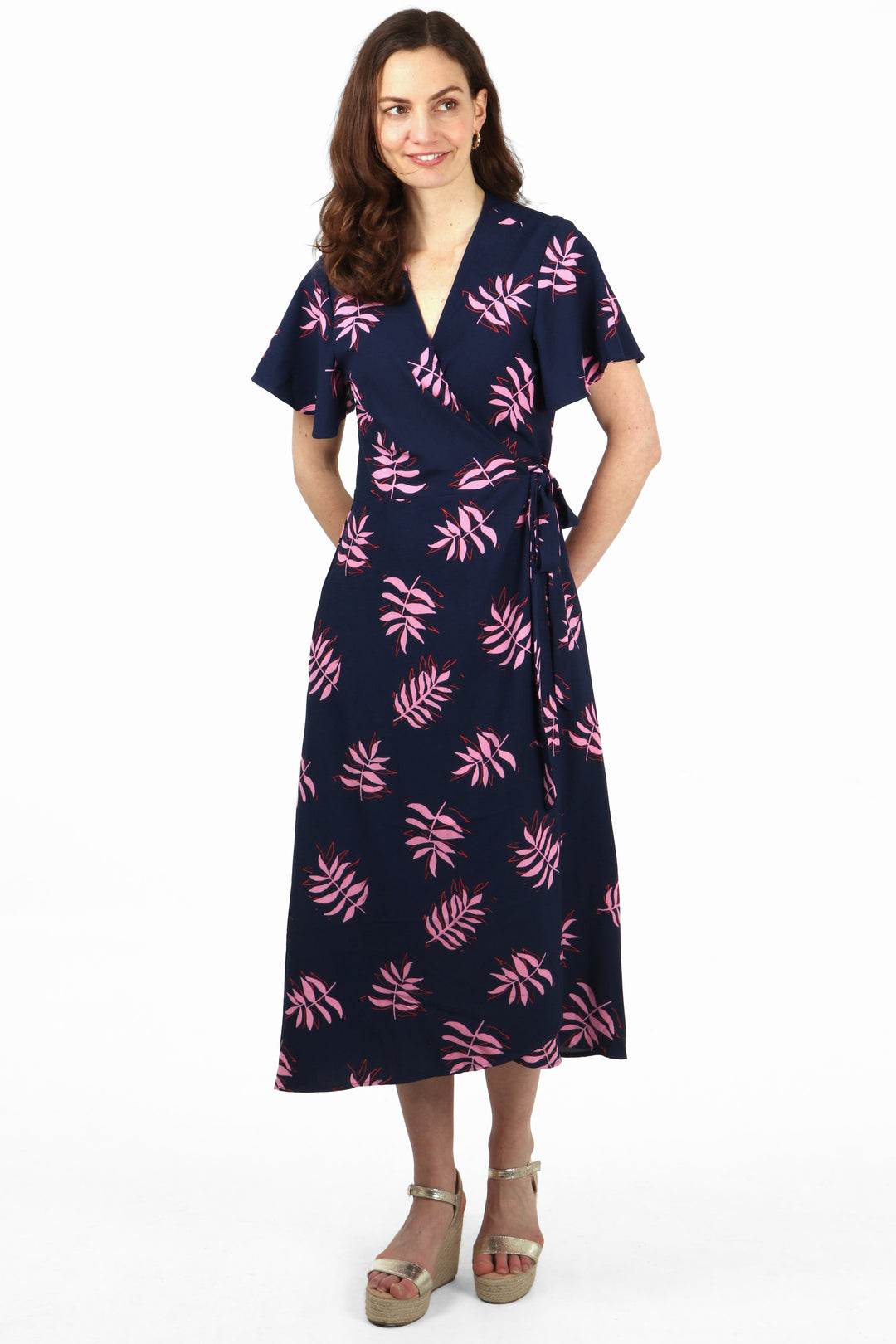 model wearing a maxi dip hem wrap dress with short sleeves, v neck and all over palm leaf pattern