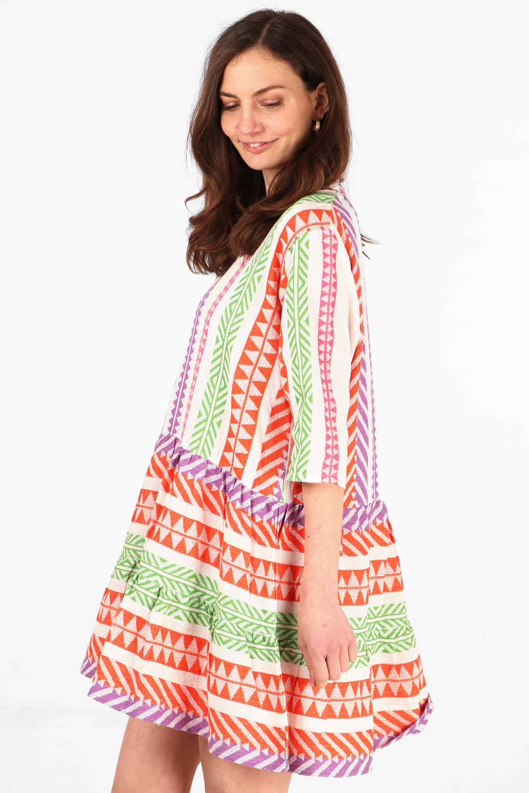 model showing the side view of the mini dress, showing the 3/4 sleeves and multi-coloured aztec pattern