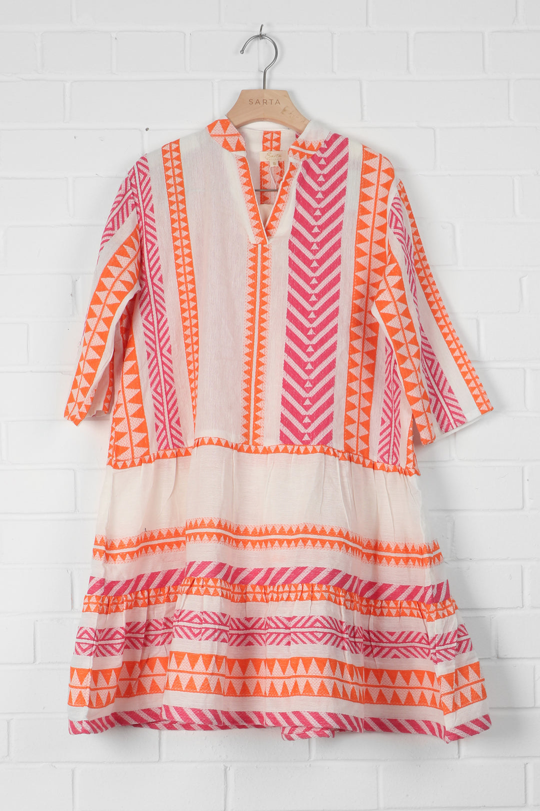 pink, orange and cream aztec pattern mini dress draped on a coathanger