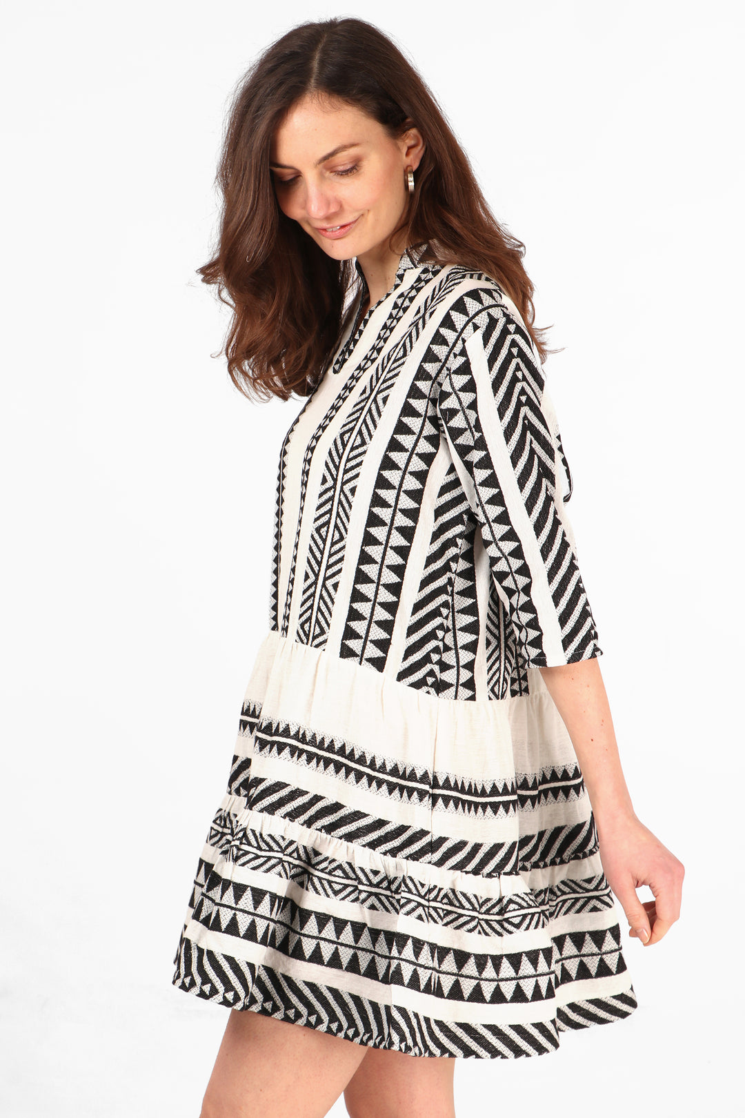 model showing the side view of the mini dress, showing the 3/4 sleeves and black and white aztec pattern