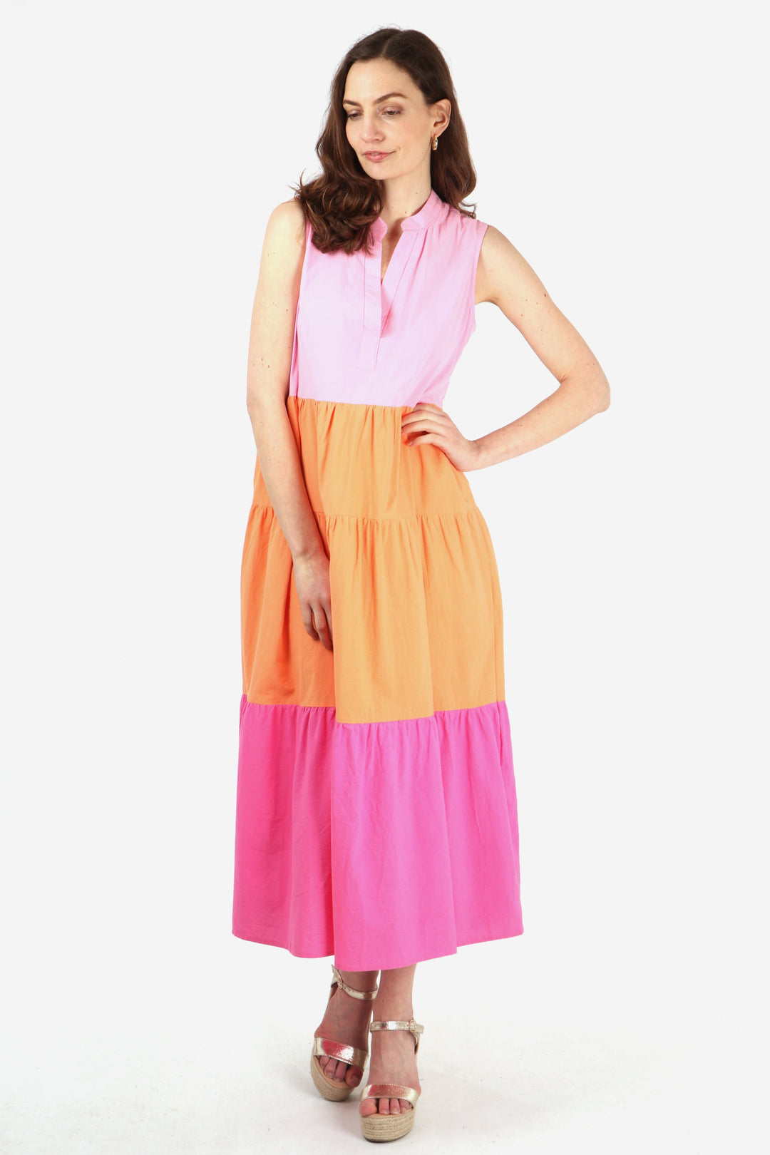 model wearing a midaxi length sleeveless cotton dress with a grandad collar in a pattern of three bold colour block stripes, baby pink bodice, orange mid section and hot pink bottom tier