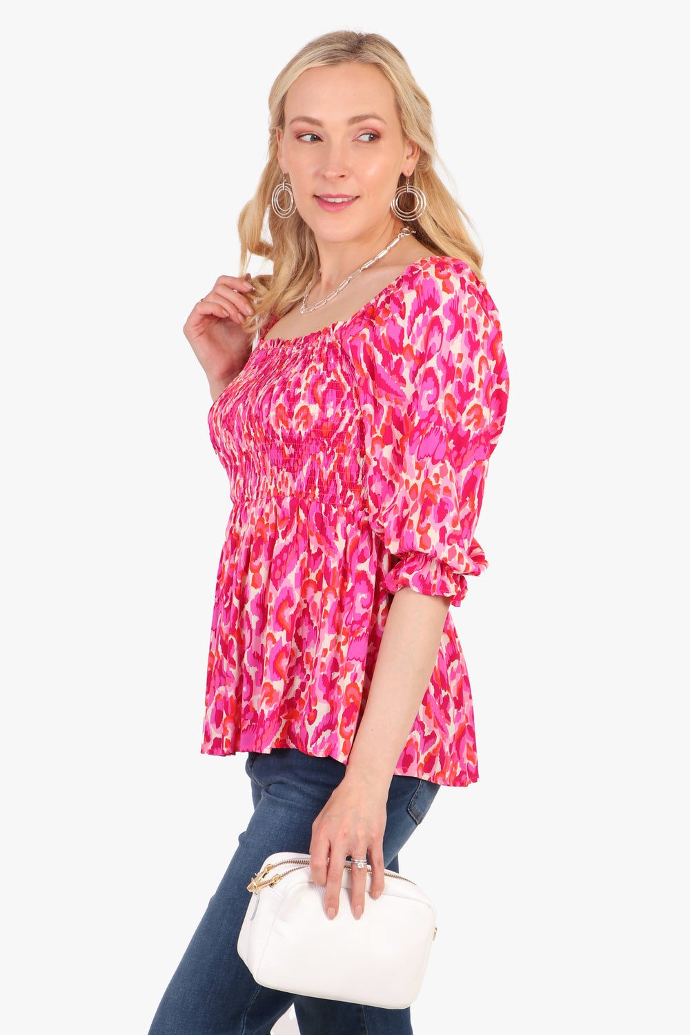 model showing the side view of the pink peplum milkmaid top, showing the 3/4 sleeves and square neck