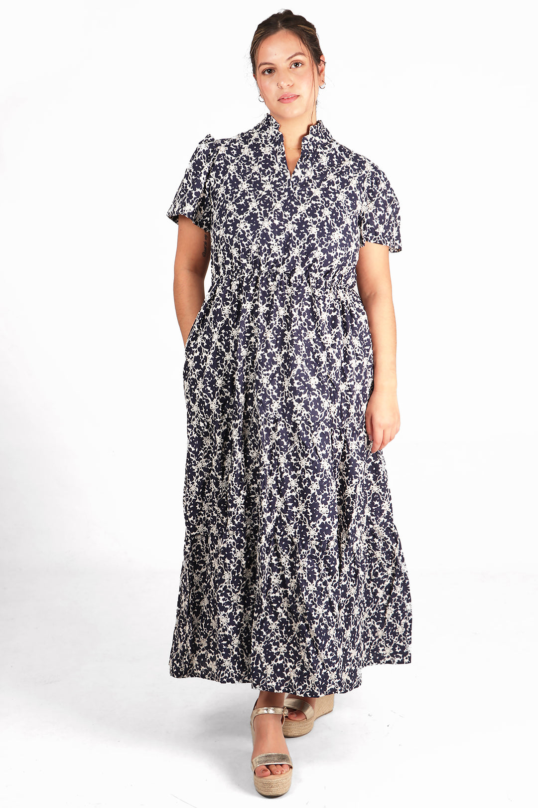 model wearing a maxi cotton dress with an all over floral broderie anglaise pattern, the dress is navy blue and white with short sleeves 