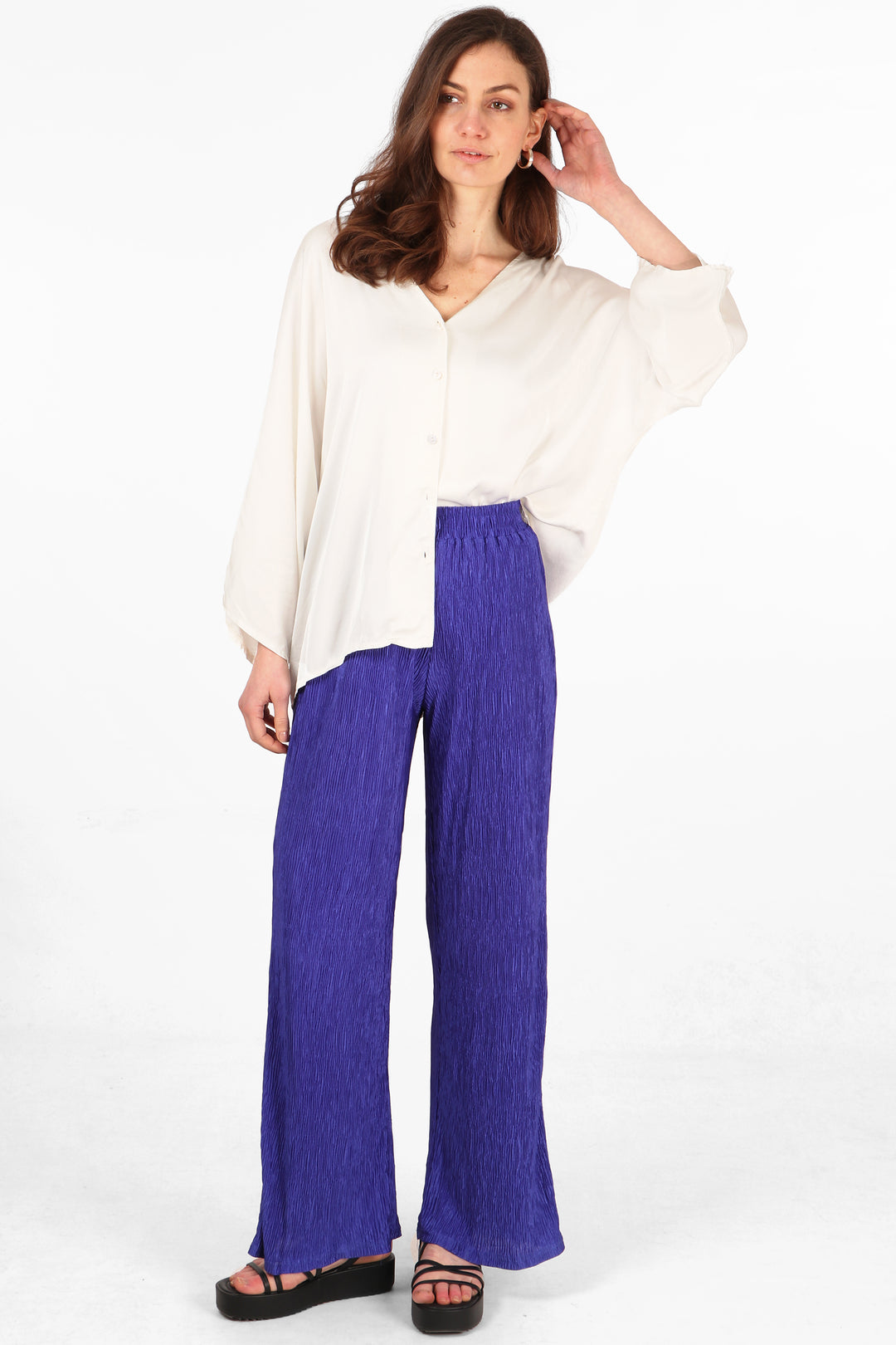 model wearing a pair of plisse material long trousers in an royal blue colour
