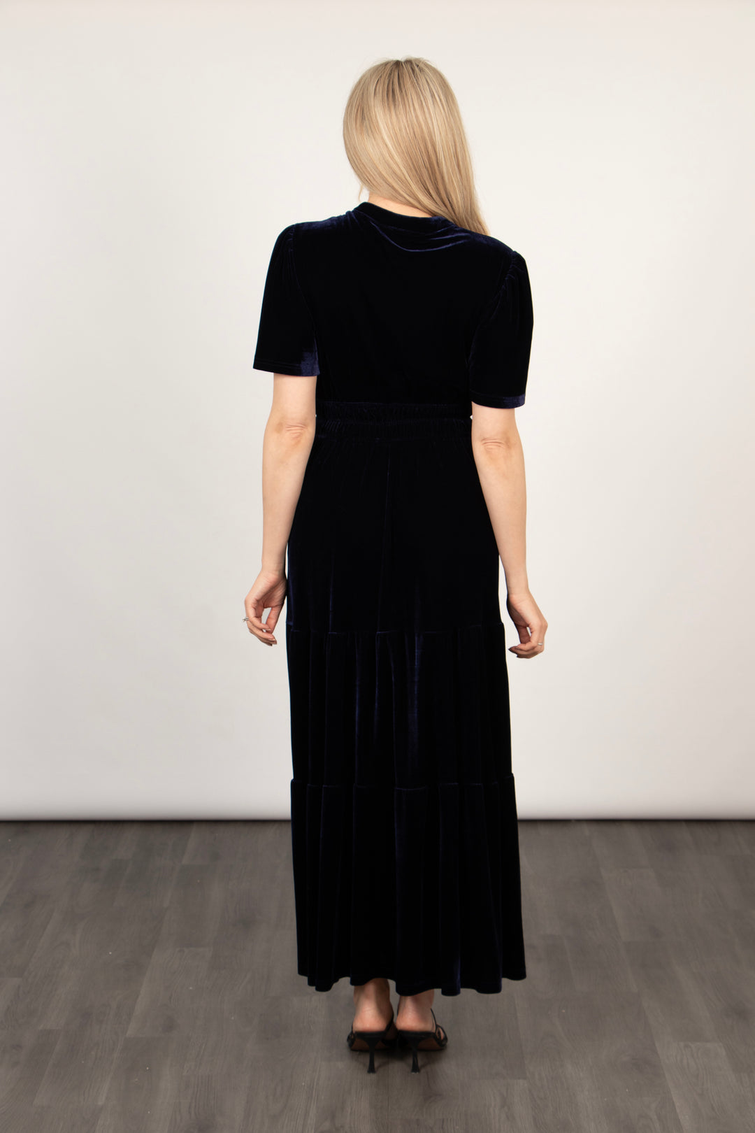 the back of the navy blue velvet maxi dress, showing the short sleeves and tiered hem