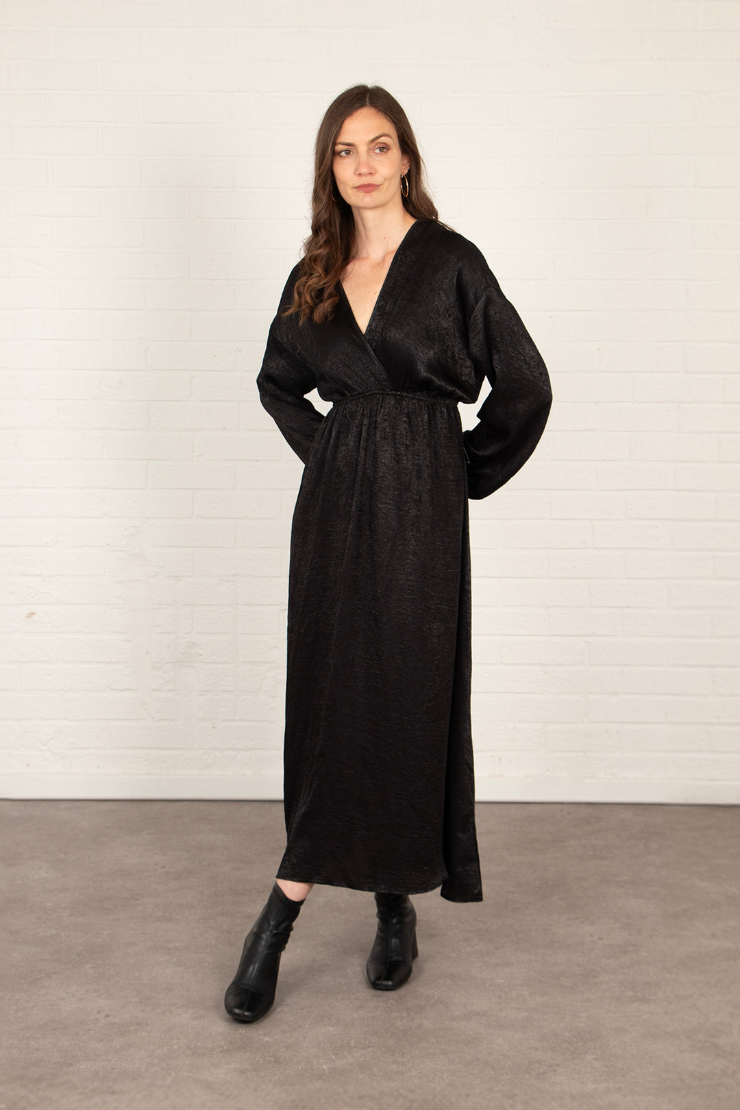 model wearing a metallic black long sleeve maxi dress with a faux wrap top and empire waist