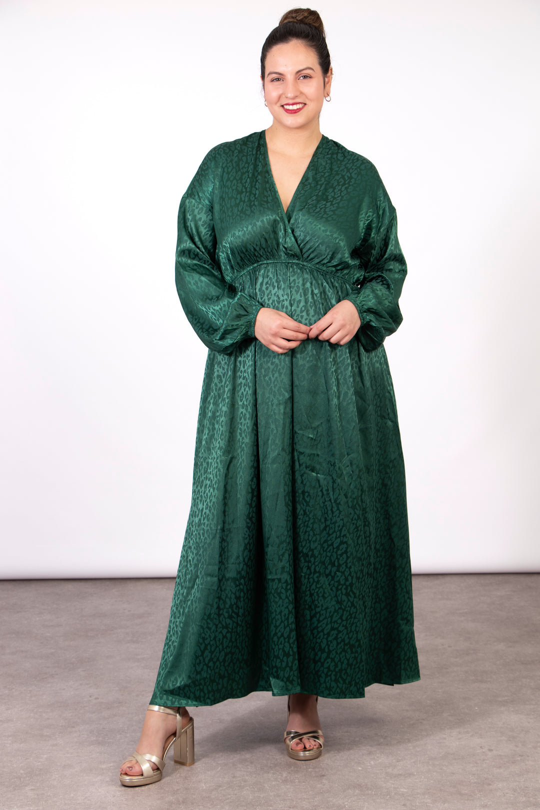 model wearing a silky green leopard print maxi dress with a faux wrap top, long sleeves and a deep v-neck