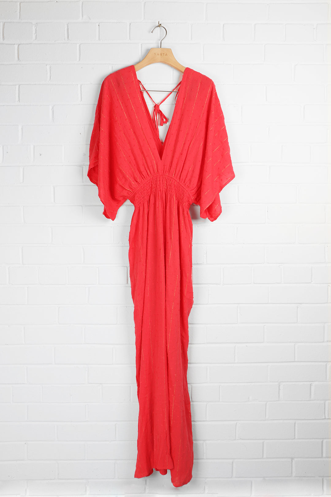 coral and gold metallic stripe jumpsuit on a coat hanger