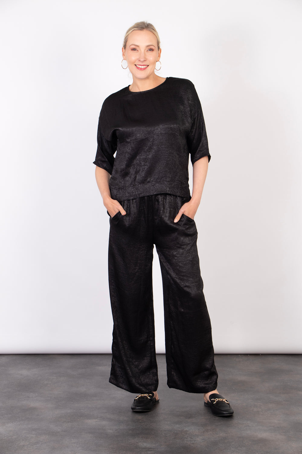 model wearing relaxed fitting black trousers, showing that they have pockets on the front