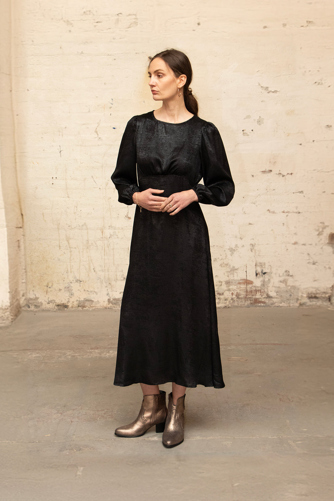model wearing the black dress accessorised with gold boots.