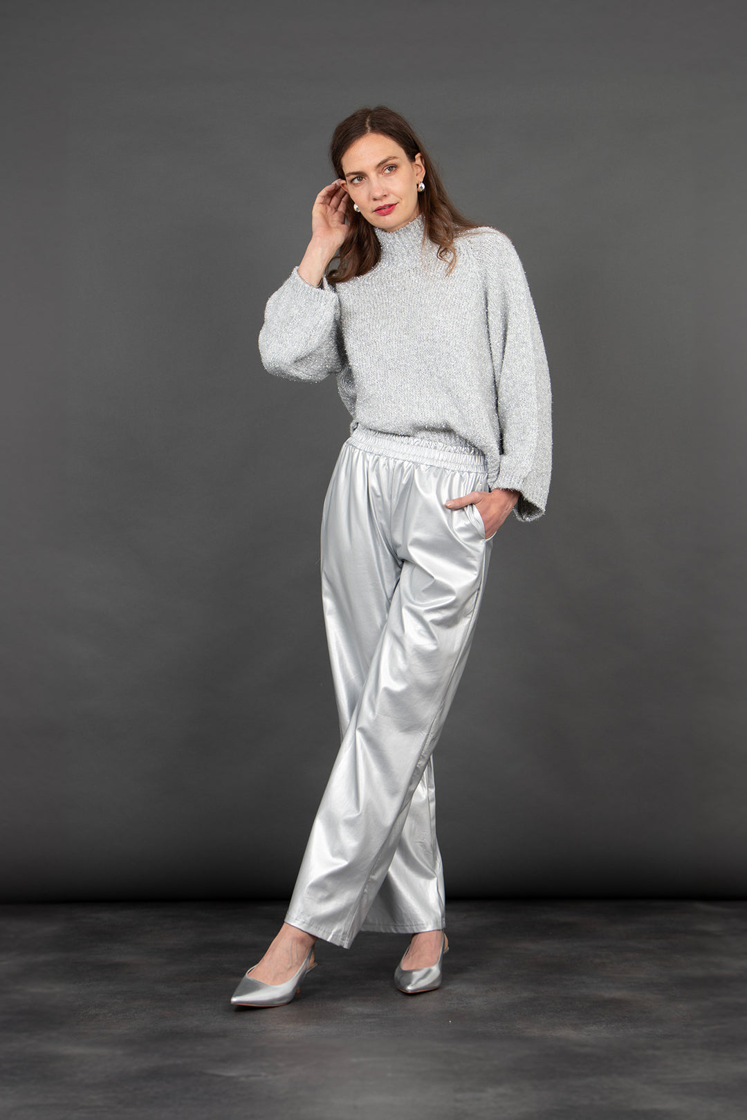 model wearing silver faux leather trousers, showing that they have pockets