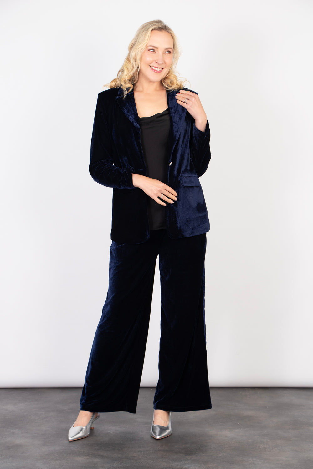 model wearing a navy blue velvet trousers paired with a matching navy blue velvet blazer