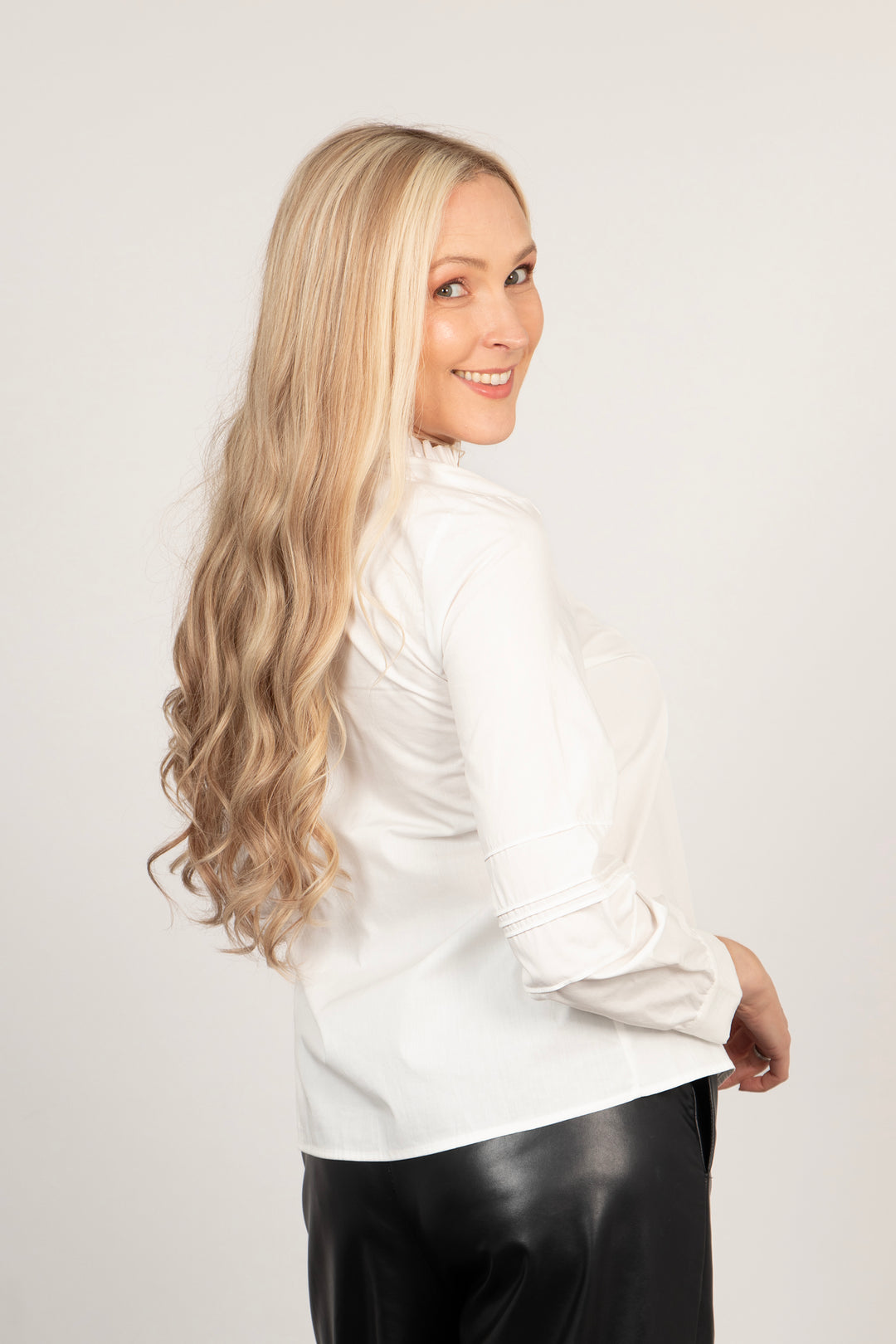 model showing a side view of the white cotton shirt, showing the pleated long sleeves