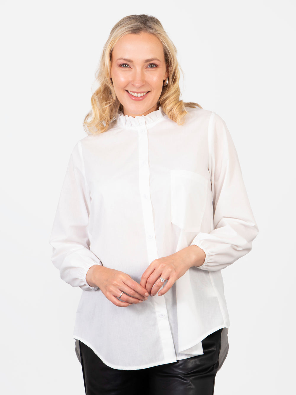 model wearing a plain white long sleeved cotton blouse with a button down front and ruffled collar