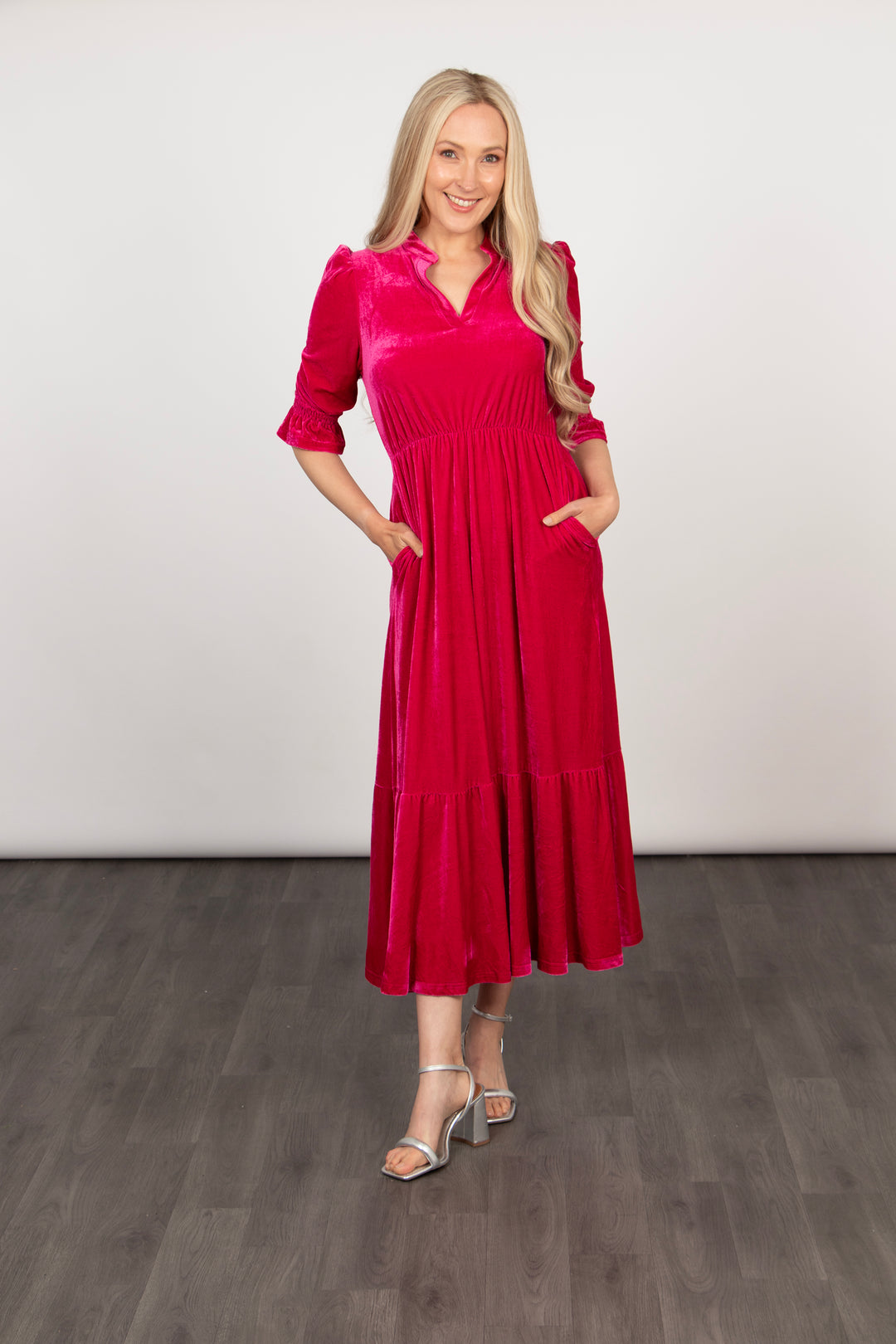 model showing that the pink velvet midi dress has pockets on the side. 