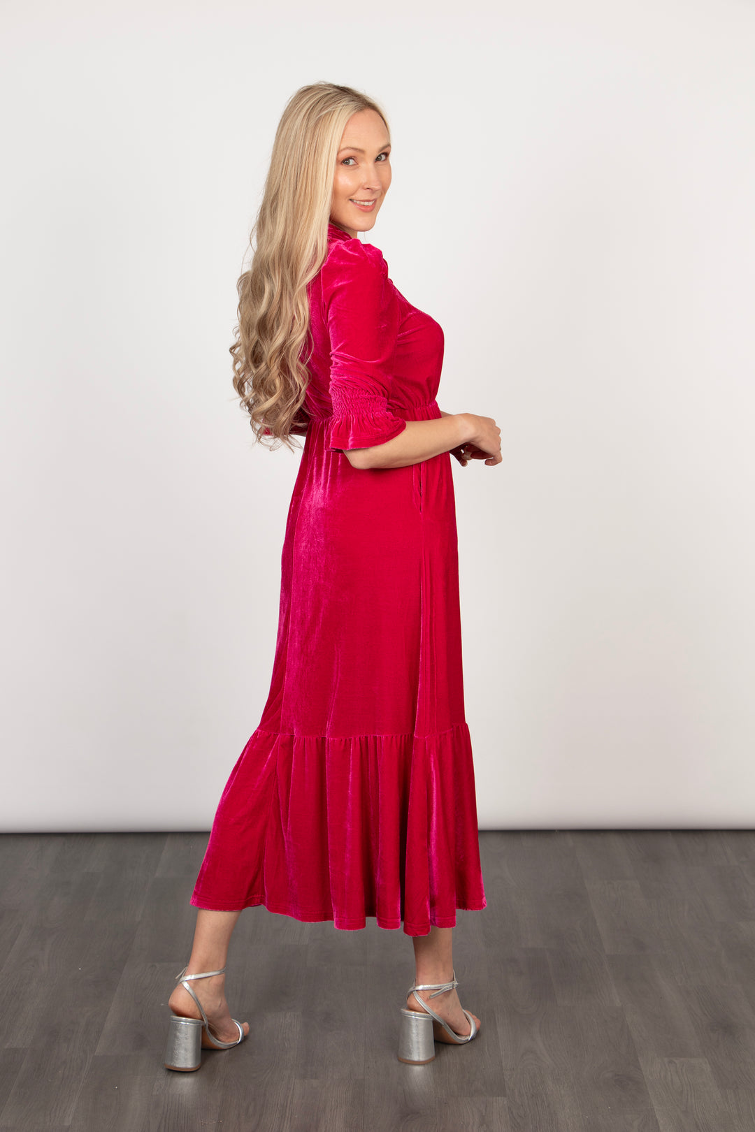 model showing the back of the dress, it is midi length with a tiered hem and 3/4 length fluted cuffs