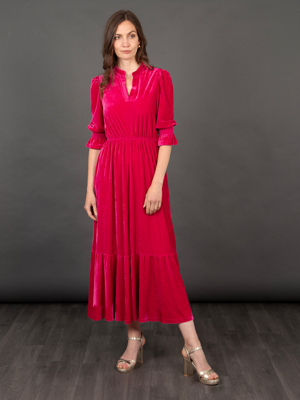 model wearing a raspberry pink tiered midaxi dress with 3/4 fluted sleeves and an open v-neck