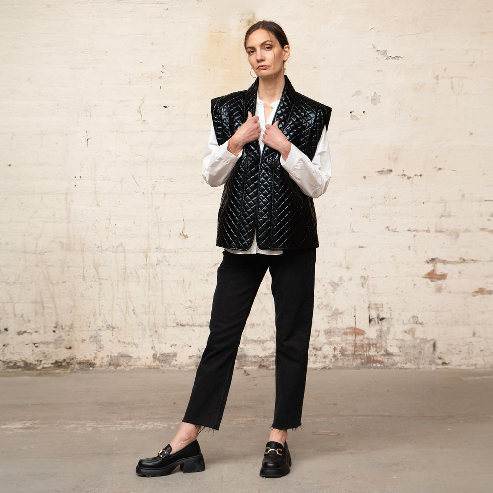 model wearing an open front shiny black quilted gilet