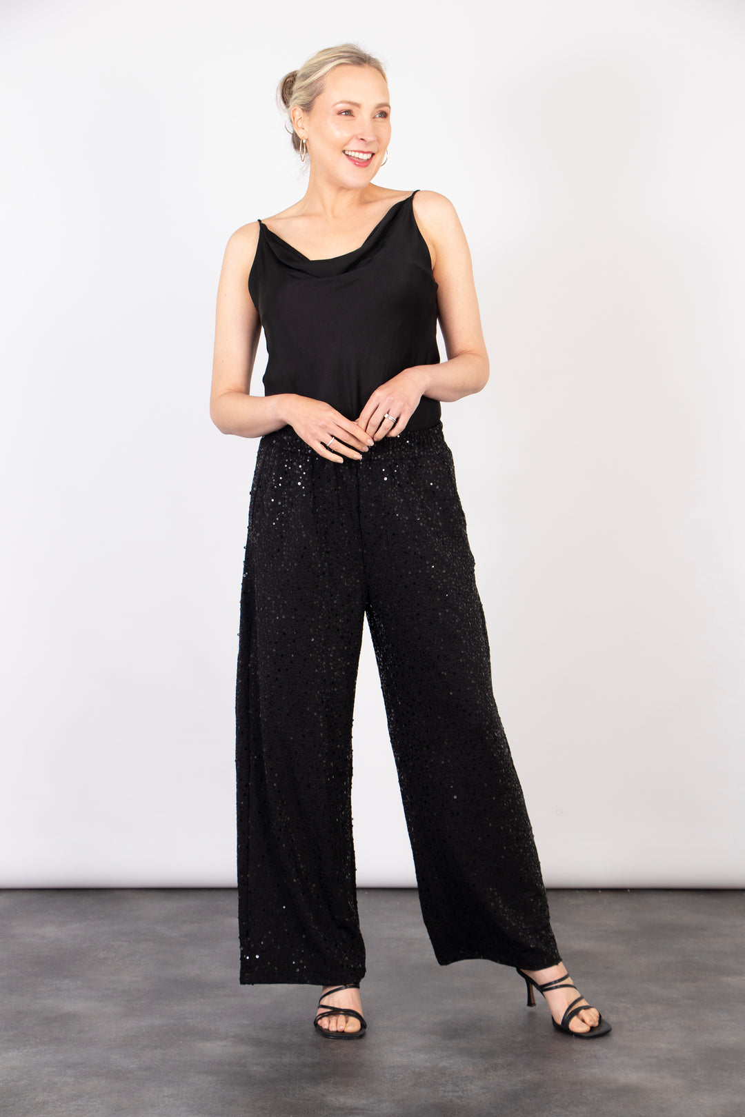 model showing the wide leg design of the black sequin trousers. 